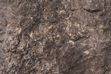 A stone wall with a rough surface. Dark gray natural background with a convex texture. Natural background in grunge style.
