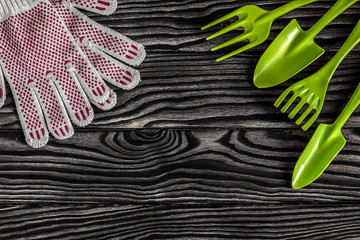 Gardening tools concept. Spade, fork, rake and gloves on black white wooden background with space...