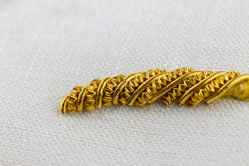 macro shot of a sample of three dimensional goldwork embroidery stitching. Padding raises the...