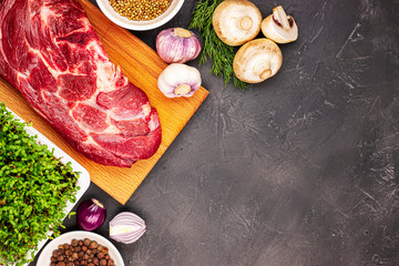 fresh raw beef with vegetables and microgreen on a black marble background, top view