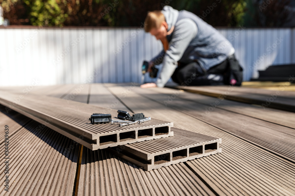 Wall mural wpc terrace construction - worker installing wood plastic composite decking boards