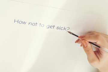 Female hands write on a sheet of paper how not to get sick