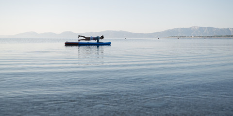 Young woman making plank position on sup board