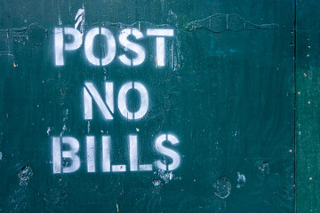 post no bills spray painted text letters on closed off unrban contrustion area