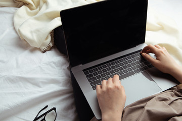 Woman in the bed with computer and glasses isolated