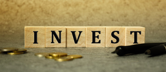 finance, inscription on cubes, word invest on cubes of wooden texture.