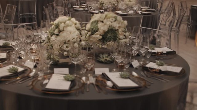 Served grey round table with a white floral centerpiece made of white eustomas at the fancy restaurant, glassware and cutlery