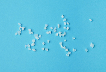 Sea salt granules isolated on blue background.