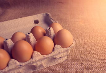 Close up of fresh raw organic chicken eggs in egg box on natural fabric background with copy space. Local organic food. Selective focus