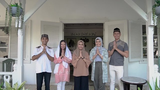 muslim family and friend greeting looking at camera standing in front of the house during eid mubarak