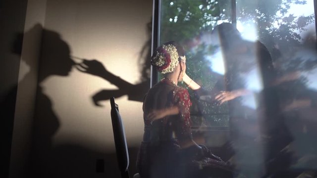 Back view of an indian girl in traditional clothes and make up process, indian wedding visage, shadow on the wall of visage process
