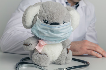 Little toy koala in the mask on the desk. Stay at home in pandemic time