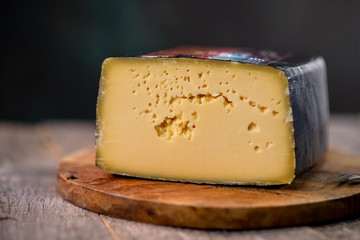 Medium hard cheese head gouda edam on wooden board with knife wooden texture daylight