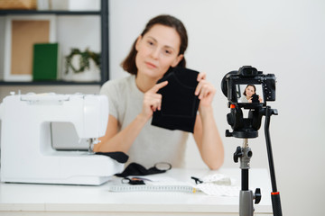 Young woman shoots a video lesson on how to make a protective mask at home.