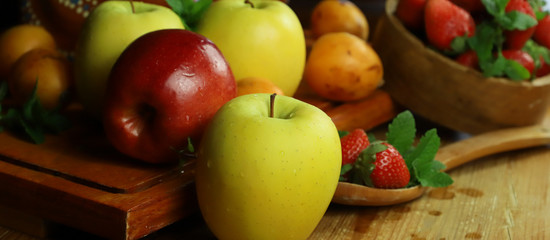 closeup of apples, strawberries and medlars in a rustic composition under a warm light