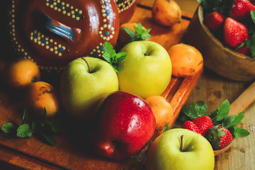 closeup of apples, strawberries and medlars in a rustic composition under a warm light