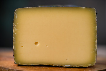 Medium hard cheese head gouda edam on wooden board with knife wooden texture daylight