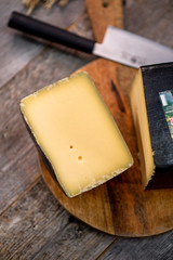 Medium hard cheese head gouda edam on wooden board with knife wooden texture daylight