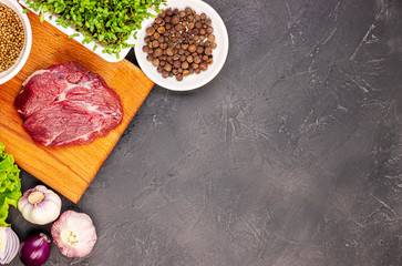 fresh raw beef on a chopping Board with vegetables and microgreens on a black marble background, top view. green flax sprouts with red meat
