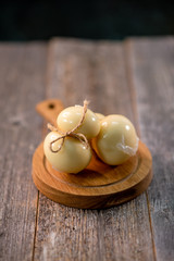 Medium hard cheese head scamorza on wooden board with knife wooden texture daylight