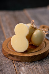 Medium hard cheese head scamorza on wooden board with knife wooden texture daylight
