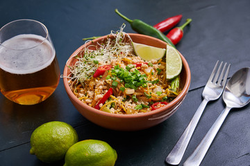Plate with spicy noodles with a glass of beer on a dark wooden table