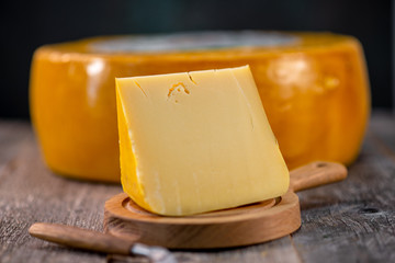 Medium hard cheese head edam gouda parmesan on wooden board with knife wooden texture daylight