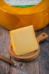 Medium hard cheese head edam gouda parmesan on wooden board with knife wooden texture daylight