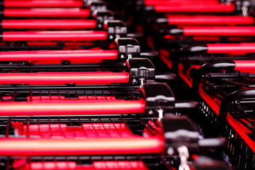 Parked red shopping carts in a row outside of store. Sanitized carts ready for customers to buy groceries after disinfection. Prevent spread of coronavirus and fight against covid-19 global pandemic.