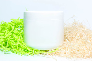 white jar with cosmetics on a white and green background