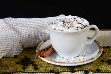 cup of coffee with milk and whipped cream on the table with roasted coffee beans