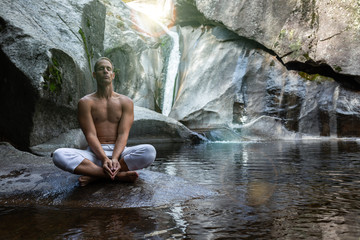 Fototapeta na wymiar young athletic boy doing iodine and meditation in a waterfall