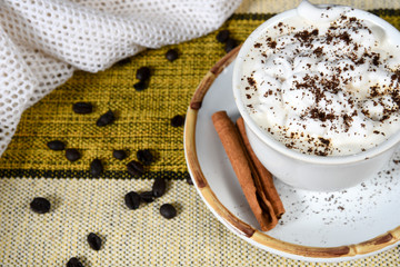 cup of coffee with milk and whipped cream on the table with roasted coffee beans