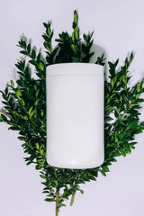 white jar with cosmetics on a white and green background