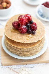 Raw vegan pancakes on a wooden plate with raspberries on top. Healthy eating lifestyle.