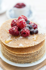 Raw vegan pancakes with honey and birch sugar on a wooden plate with raspberries on top. Healthy eating lifestyle.
