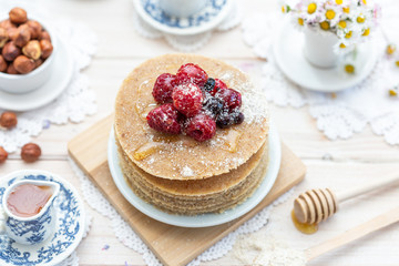 Raw vegan pancakes with honey and birch sugar on a wooden plate with raspberries on top. Healthy eating lifestyle.