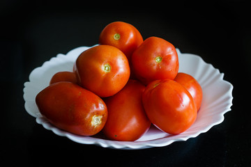 Varios tomates en un plato  con fondo negro