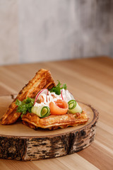 Presentable plating of Belgian waffle topped with vegetables and salmon for healthy living lifestyle. Food photography concept for magazine or online delivery menu.