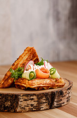 Presentable plating of Belgian waffle topped with vegetables and salmon for healthy living lifestyle. Food photography concept for magazine or online delivery menu.