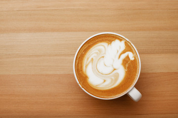 Coffee latte with nice and presentable plating in a white mug top view in wooden table background. Hot beverage photography with space available for text.