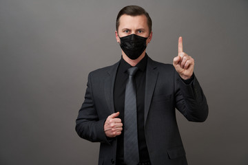 Businessman with surgical medical mask pointing with finger.