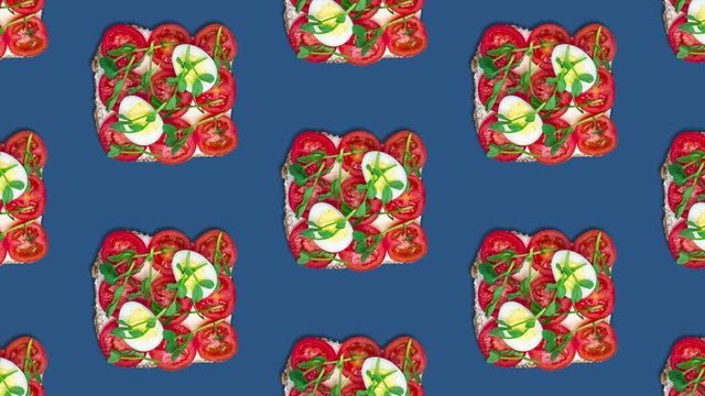 Pattern eating a toast with cream cheese, tomatoes, quail eggs and pea sprouts. Healthy food concept, looped stop motion animation, top view. Classic blue background, color of the year 2020