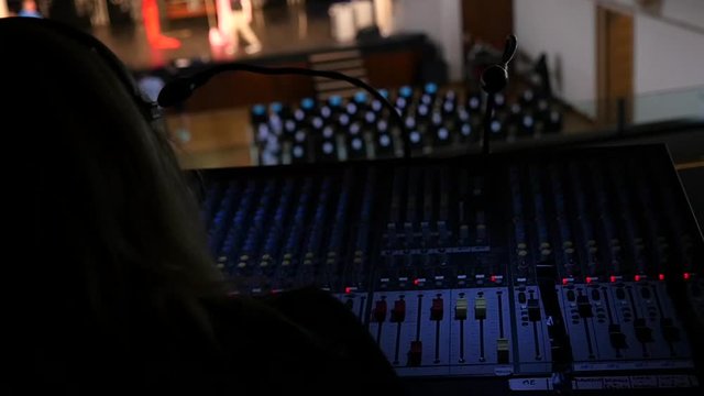 Sound engineer girl behing her mixing console in theatre