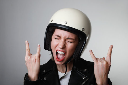Biker woman with helmet and leather outfit. Emotional face of biker woman, posing on the white background.