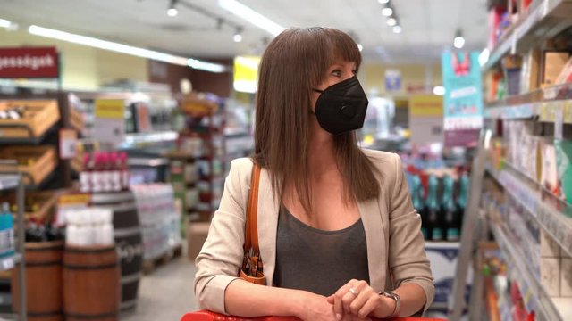 Young woman in face mask shopping in grocery store supermarket.