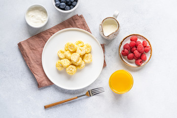  Curd and cheese dumplings served with berries and sour cream on a ceramic white plate. Traditional Ukrainian or Russian lazy dumplings (vareniki). Healthy Breakfast, top view.