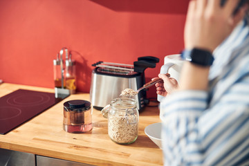 Caucasian lady fetching cereal from jar at home