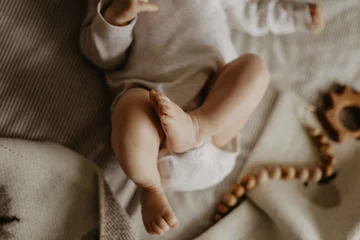 Fototapeten legs of a baby lying on a beige plaid and wooden toys on the background © annaperevozkina