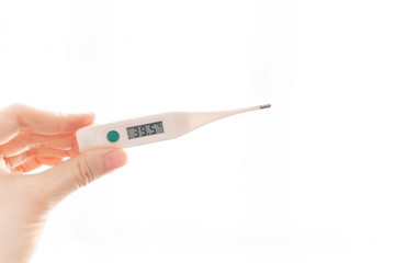 The fingers of a female hand hold an electronic thermometer with a temperature of 39.5 degrees on...